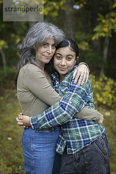 Porträt einer weißen Mutter und ihrer gemischtrassigen Teenager-Tochter  die sich umarmen