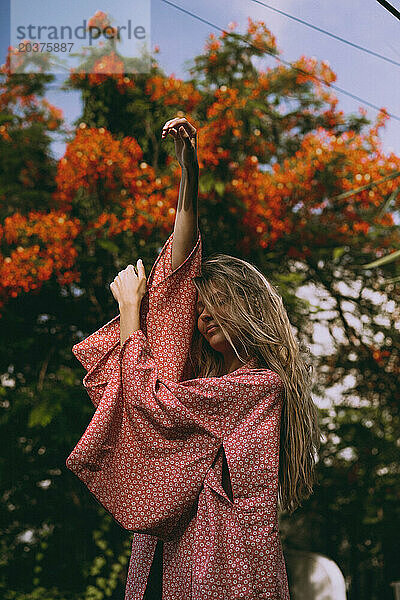 Junge Frau mit langen Haaren im Kimono geht auf Bali die Straße entlang.