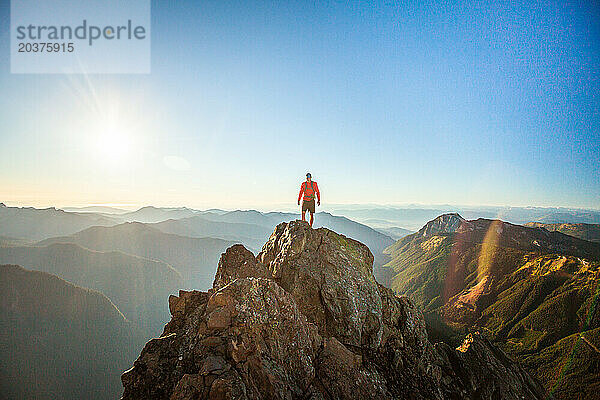 Erfolgreicher Wanderer steht auf dem Gipfel eines felsigen Berges