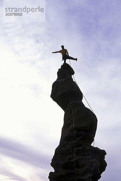 Mann balanciert auf einer Bergsäule in Utah. (Silhouette)