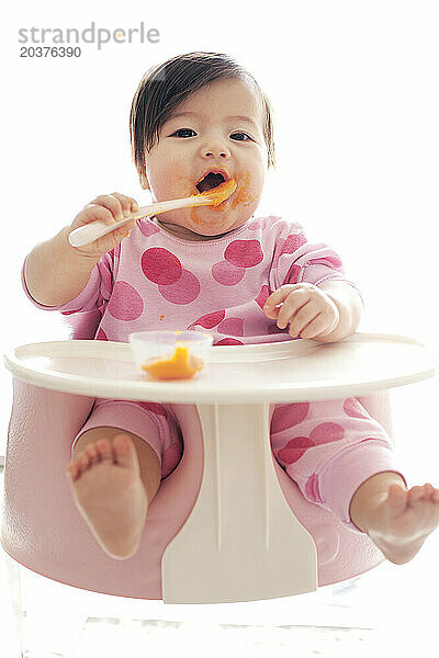 Ein Baby lernt  sich selbst zu ernähren  während es in einem Kindersitz in New York  New York  sitzt.