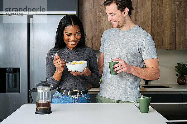 Multiethnisches Paar hat Spaß beim Frühstück in der Küche.