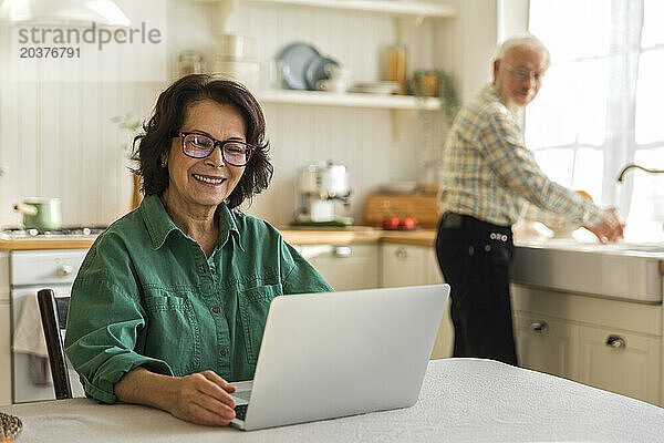 Ältere  fröhliche Frau mit Brille nutzt lächelnd den Laptop-Bildschirm
