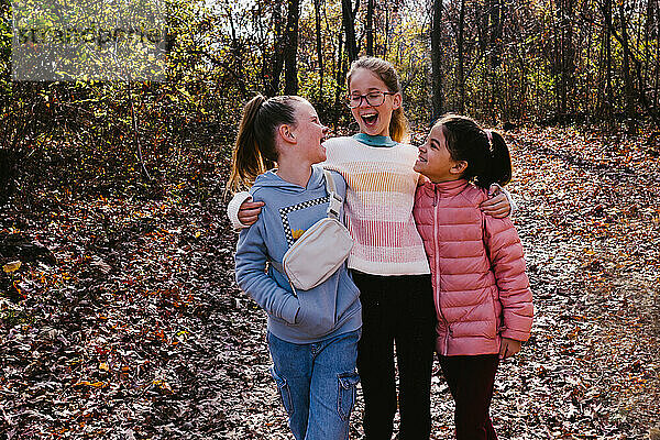 Girls laugh and talk of multi race in fall leaves in forest