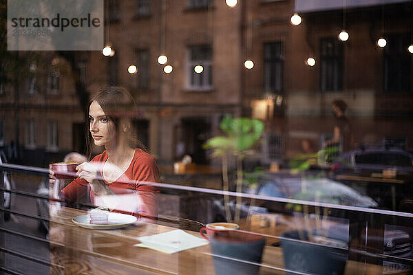 Außenansicht des Cafés mit einer jungen Frau  die drinnen am Fenster sitzt