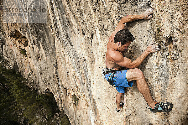 Mann klettert eine schwierige Route auf Kalkstein auf Mallorca  Spanien.