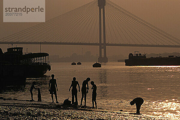 Männer waschen sich im Hooghly River bei Sonnenuntergang am Babu Ghat in Kalkutta  Indien. Der Fluss ist heilig  da das Wasser verschmutzt ist.