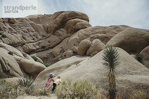 Zwei Kinder starren zu hohen Felsen in Joshua Tree