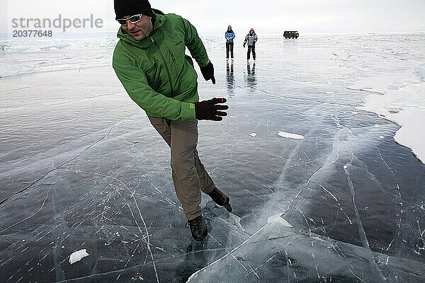 Drei Personen Eislaufen auf dem zugefrorenen Baikalsee  Sibirien  Russland.