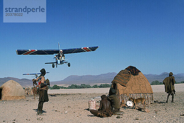 Zwei Menschen fliegen mit ihrem Ultraleichtflugzeug über die Wüste Namibias.