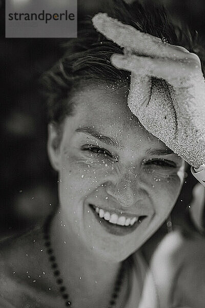Glückliche  lächelnde  lachende Frau am Strand  Porträt  Sand im Gesicht.