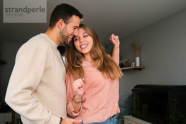 Spanisches Paar tanzt und lacht zu Hause zusammen.