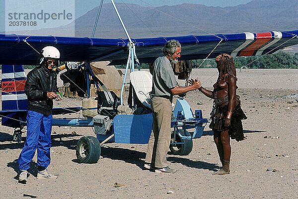 Drei Menschen grüßen andere in der Wüste  Namibia.