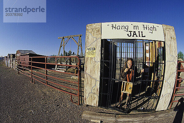 Eine Frau in einer Westernstadt hinter alten Gefängnisgittern.