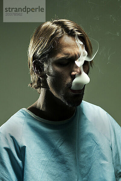 Ein als Patient verkleideter Mann atmet aus  nachdem er medizinisches Marihuana geraucht hat.