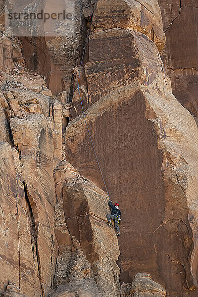 Entschlossener Bergsteiger klettert felsige Klippe in der Wüste