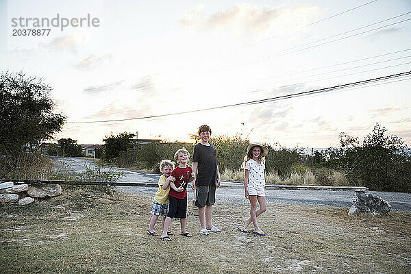 Vier lächelnde Geschwister posieren gemeinsam bei Sonnenuntergang im Urlaub in Anguilla