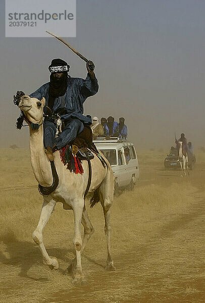 Ein Toureg reitet auf seinem Kamel in einem gemischten Konvoi aus Autos und Kamelen durch die Sahelzone  Gao  Mali  Westafrika