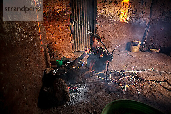 Tansanisches Mädchen kocht auf einem Steinofen