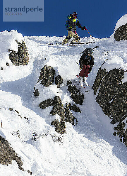 Ein Skifahrer stößt an einem sonnigen Tag am Cerro Catedral in Argentinien auf eine kleine Klippe  während sein Freund von oben zuschaut
