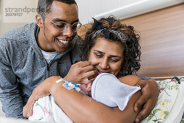 Gemischtrassiges Paar lächelt das frischgebackene Baby direkt nach der Geburt an