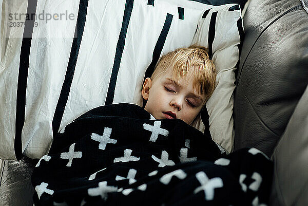 Nahaufnahme eines kleinen Jungen  der tagsüber auf einer einfarbigen Decke schläft