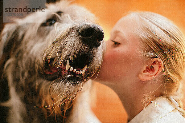 Kleines Mädchen küsst Hund.