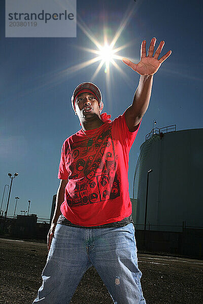 Ein afroamerikanischer Rapper und Tänzer posiert für ein Porträt in einer Stadtlandschaft.