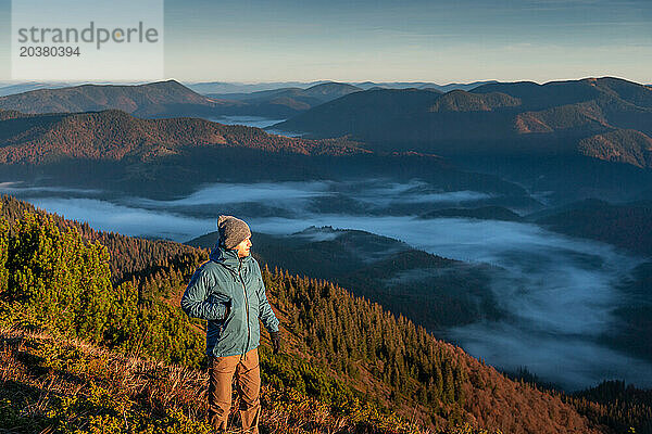 Wanderer allein mit Blick auf die Aussicht vom Berggipfel  erstes Morgenlicht