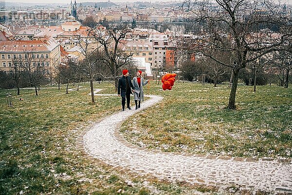 Junges Paar geht mit Luftballons im Herzen durch Prag