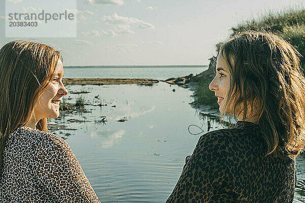 Smiling daughter spending leisure time with mother by sea