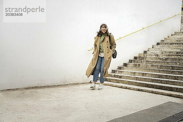 Happy woman wearing overcoat moving down on staircase