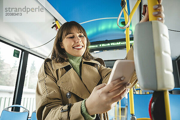 Smiling passenger buying ticket in bus through contactless payment using smart phone