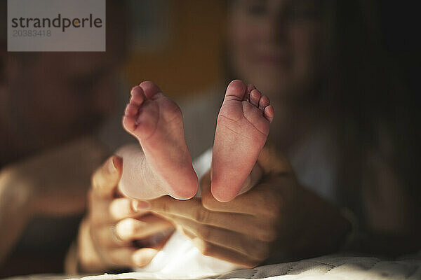 Mother holding baby boy's legs at home