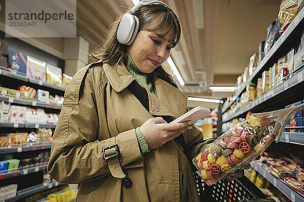 Woman using smart phone to check information of product at supermarket