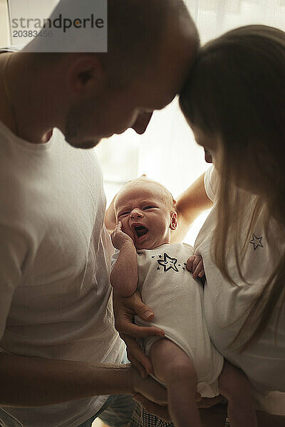 Parent holding baby boy in arms at home