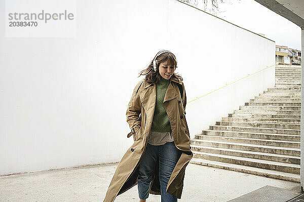 Smiling woman wearing overcoat walking near staircase