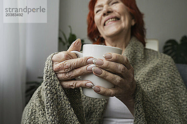 Smiling senior woman sitting with mug of tea at home