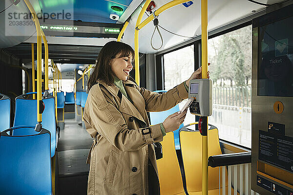 Happy passenger buying ticket in bus through contactless payment using smart phone