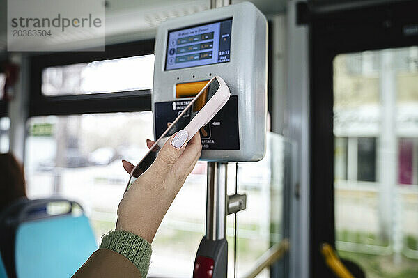 Hand of woman buying ticket in bus through smart phone