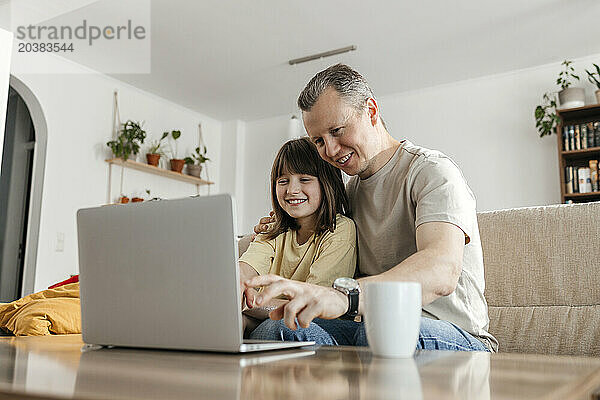 Happy father and daughter watching movie on laptop at home