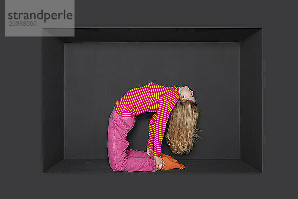 Blond teenage girl bending backward in alcove over black backward