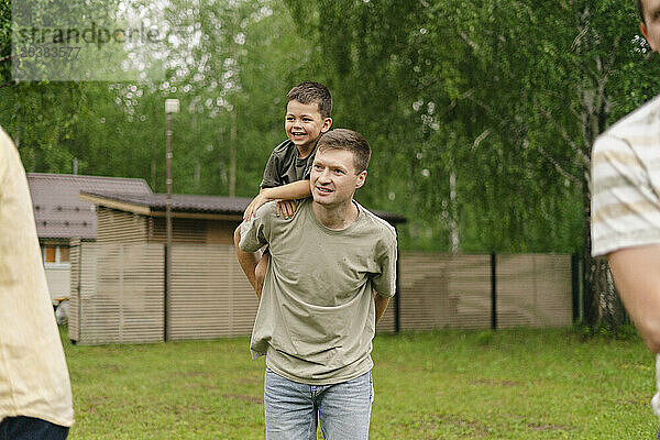 Happy father carrying son in back yard on weekend