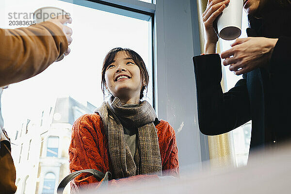 Happy young woman talking with sister and friend at cafe