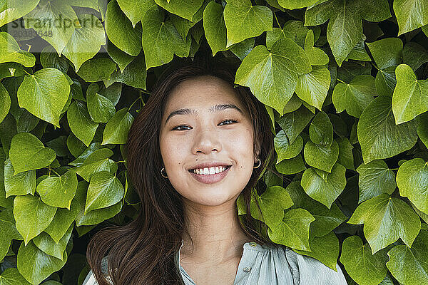 Smiling woman amidst green leaves