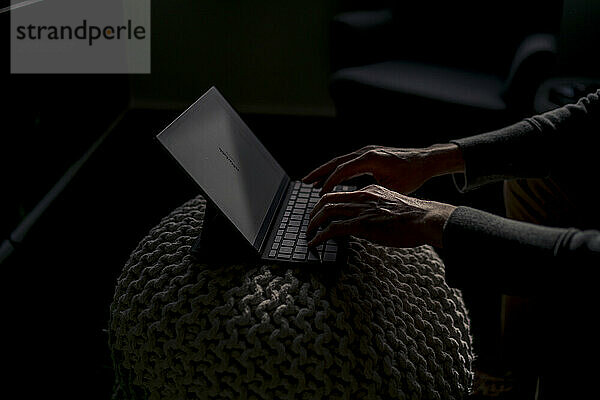 Hands of businessman working on tablet PC in dark office