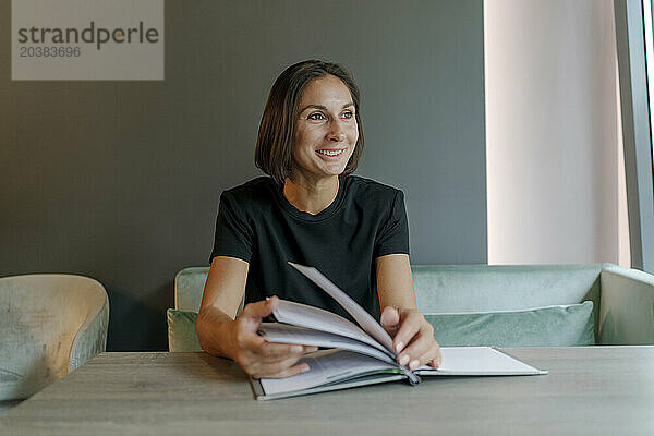 Smiling businesswoman sitting with magazine in cafe