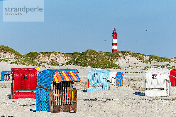 Germany  Schleswig-Holstein  Amrum  Hooded beach chairs on sandy beach with lighthouse in background