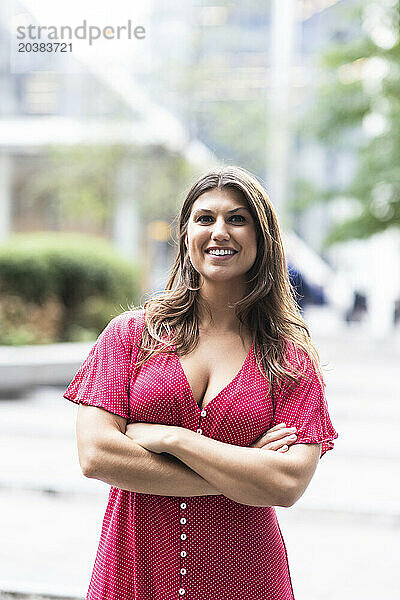 Smiling young woman standing with arms crossed