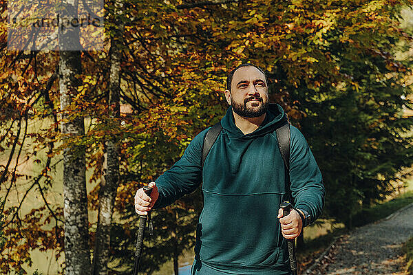 Hiker hiking with walking poles in forest